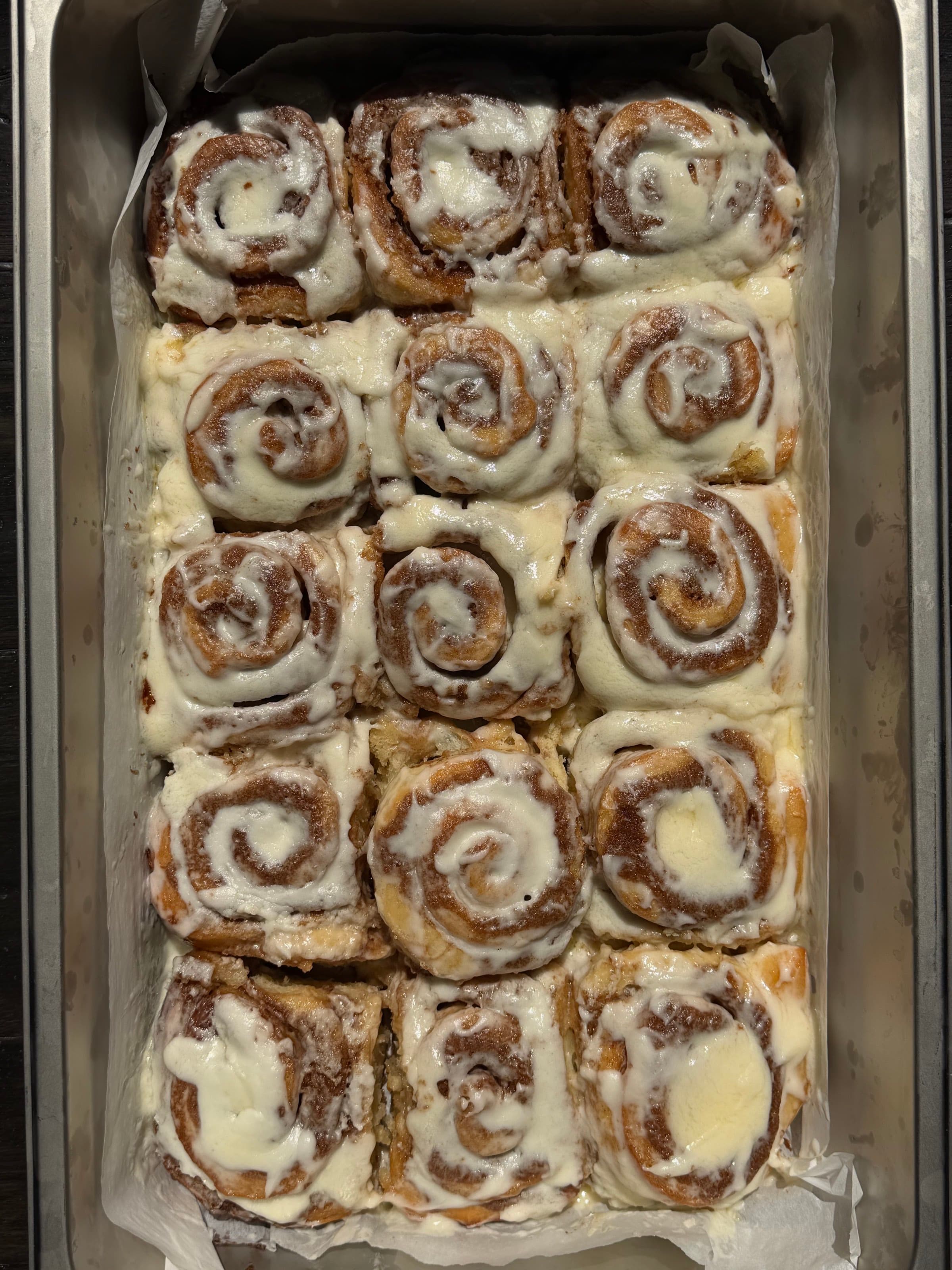A tray of Berloom cinnamon rolls under cream cheese frosting